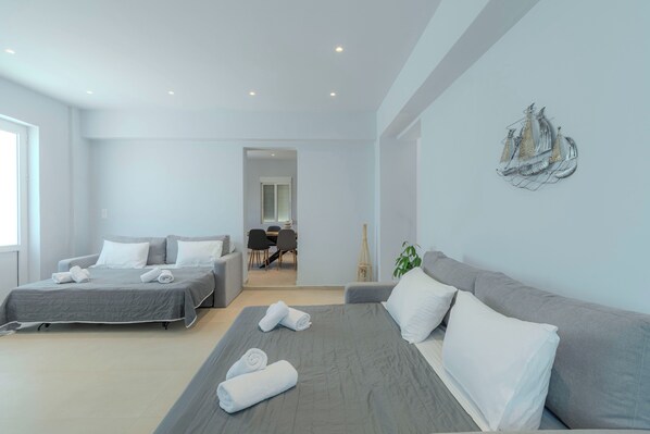 Una habitación de hotel moderna con una cama grande, dos camas más pequeñas, un sofá, un comedor y un elemento decorativo en la pared.