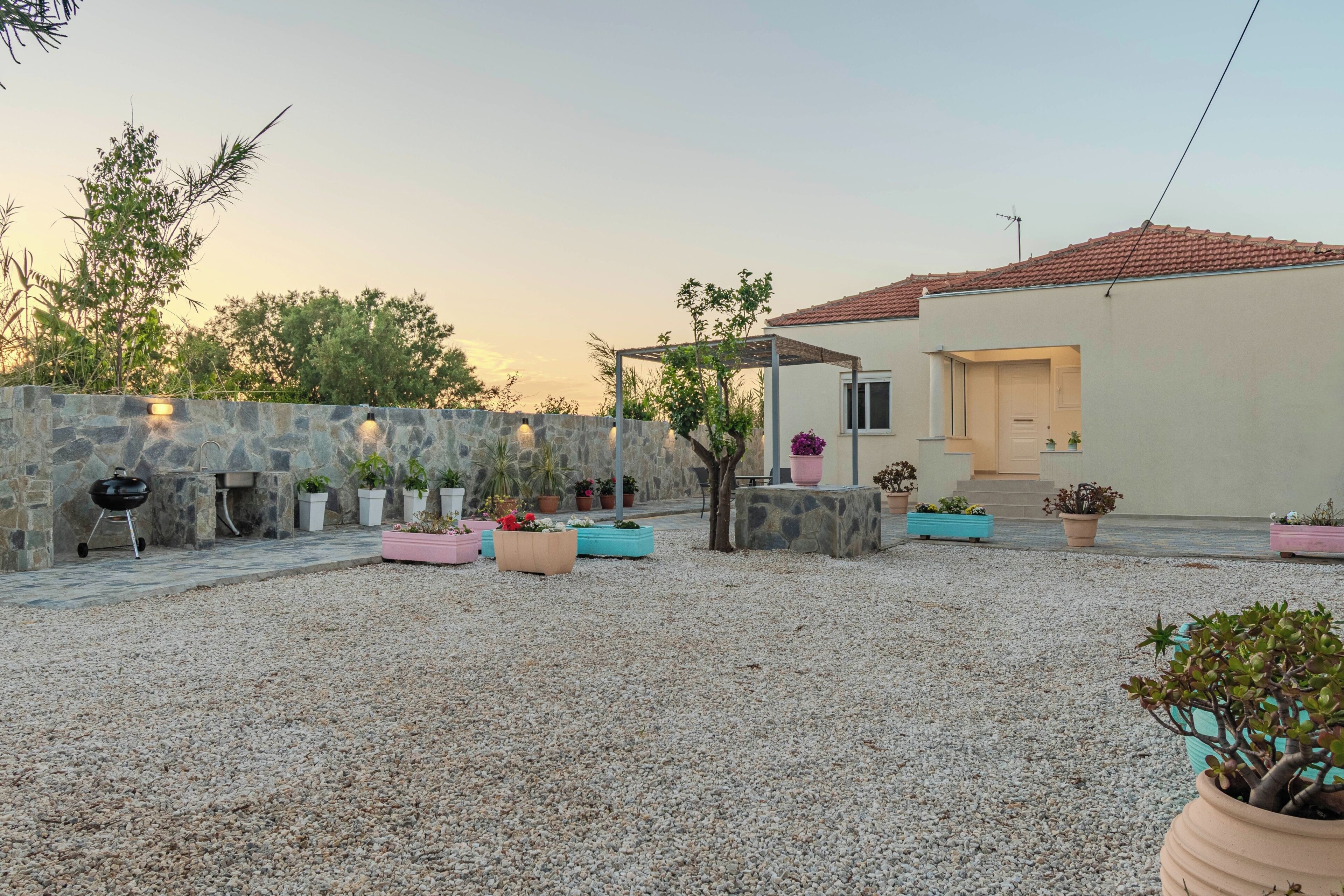 A courtyard with a stone wall, a barbecue grill, and potted plants.