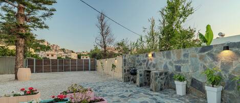 A patio area with stone flooring, outdoor seating, and potted plants.