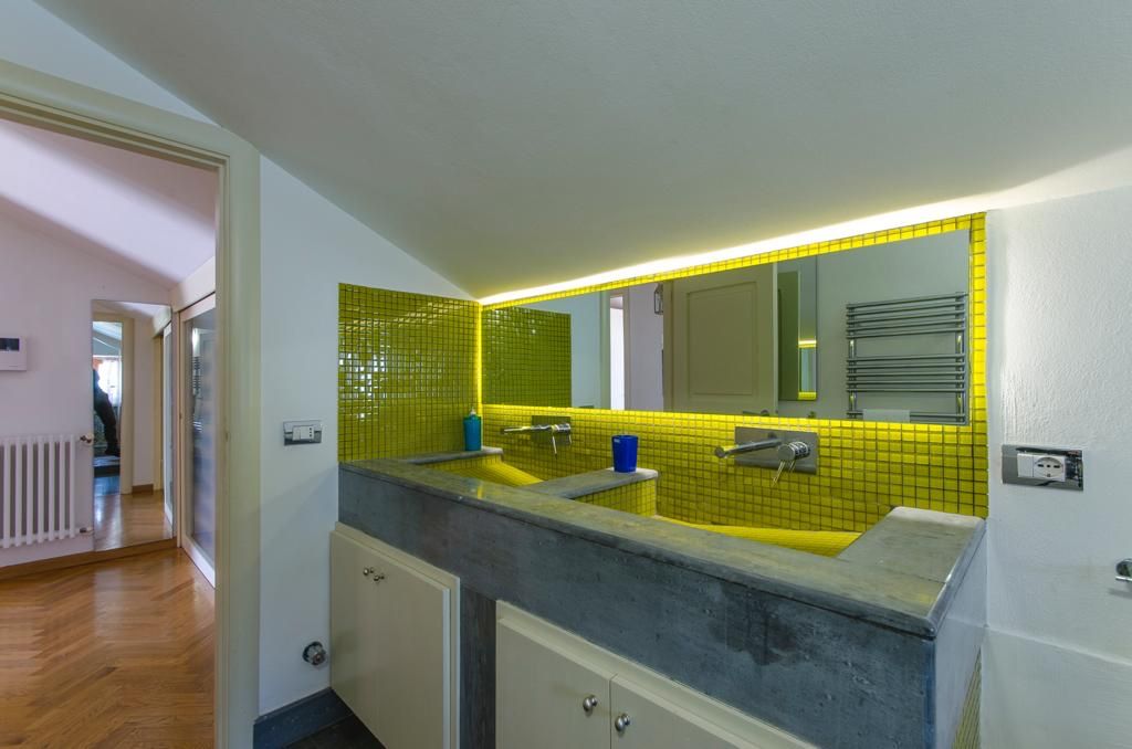 A bathroom with a double sink, a mirror, and a yellow-tiled backsplash.