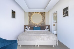 A modern bedroom with a large bed, a stone accent wall, and a round mirror. - Bellini apartament, relax cozy sea view apartment in Taormina (Sicilia)