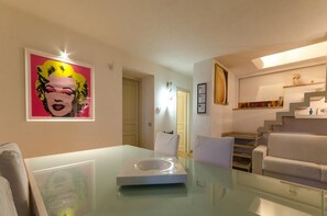 Ein modernes Interieur mit einem Glastisch, einer Treppe und einem gerahmten Kunstwerk an der Wand.