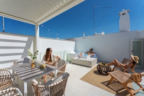 A rooftop terrace with outdoor seating, a table with a vase and fruit, and a lounge area with a sofa and a round table. - Volta Nova Collection – Historic Rooftop Retreat (Polignano a Mare)
