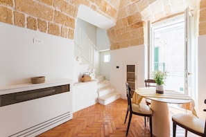 A kitchen with a herringbone floor, white cabinetry, a built-in stove, and a window overlooking a street. - Volta Nova Collection – Historic Rooftop Retreat (Polignano a Mare)