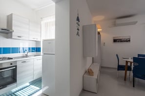 A modern kitchen with white cabinets, a blue backsplash, and a dining area with a table and chairs. - BlueLido House - Alghero (Alghero)