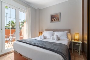 Ein Hotelzimmer mit einem Bett, zwei Nachttischen, einem Bild an der Wand und einer Glastür zum Außenbereich.