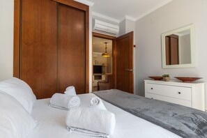 Ein Hotelzimmer mit einem Bett, einem Holzschrank, einer weißen Kommode, einem Spiegel und einer Klimaanlage.