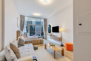 A modern living room with a sofa, coffee table, and a TV mounted on the wall. - Gogoto Lux Studio Canal & Burj View (Dubai)