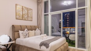 Een moderne hotelkamer met een groot bed, een bureau en een balkon met uitzicht op de stad.
