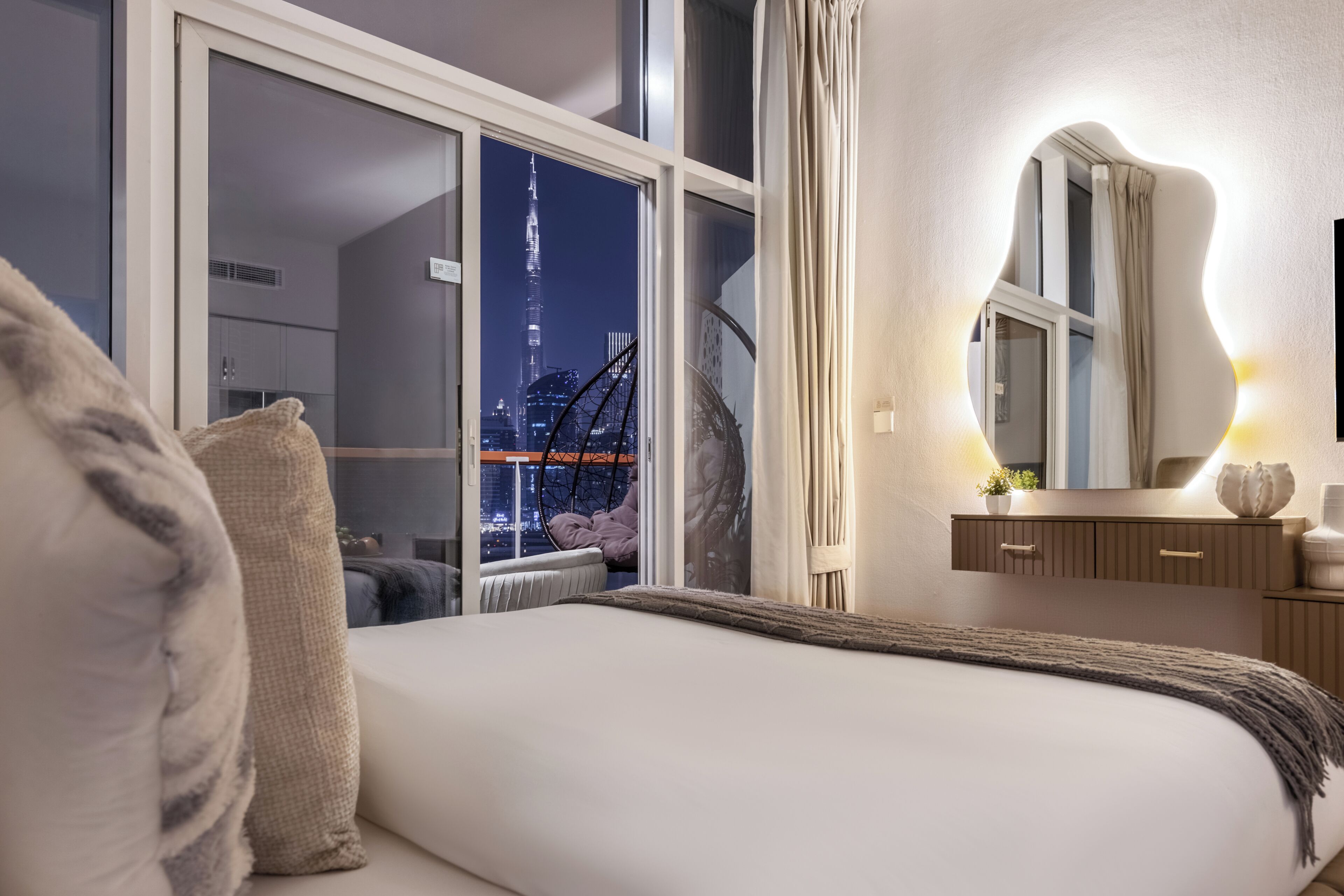Un dormitorio con una cama grande, vistas a un paisaje urbano y un baño moderno.