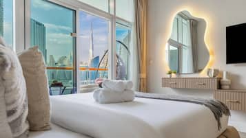 Quarto de hotel moderno com uma cama grande, vista para a cidade, um espelho amplo e uma televisão de tela plana.