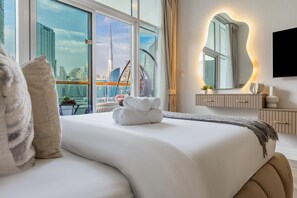 A modern hotel room with a large bed, a city view, a TV, and a minimalist decor. - Gogoto Lux Studio Canal & Burj View (Dubai)