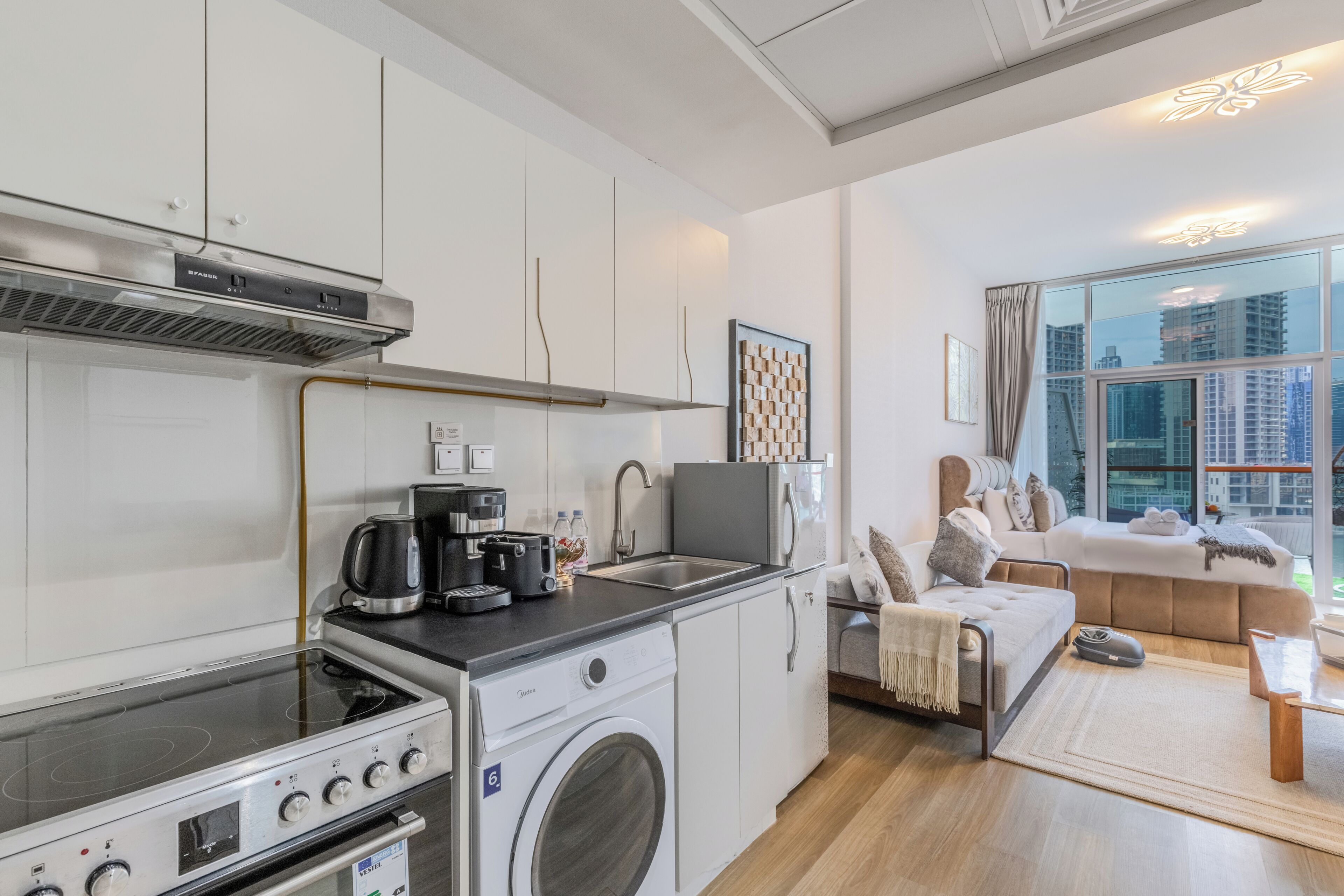 A compact kitchenette with a stove, coffee maker, and a washing machine.