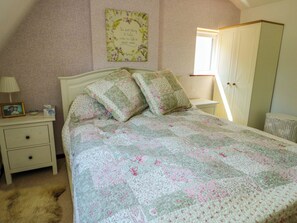 A bedroom with a bed, a nightstand, a dresser, a framed quote on the wall, and a window. - Tan-y-ffordd Cottage (Llandudno Junction)