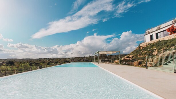 A swimming pool with a clear view of the surrounding landscape and a building with a modern design. - Exclusive villa with pool, near Noto - DiCasaInSicilia (Noto)