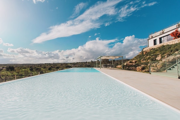 Ein Schwimmbecken mit freiem Blick auf die umliegende Landschaft und ein Gebäude im modernen Stil.