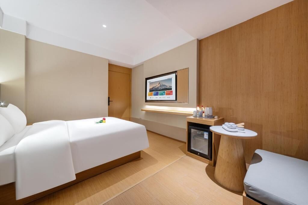 A hotel room with a bed, a small table, a TV, and a wooden panel wall.