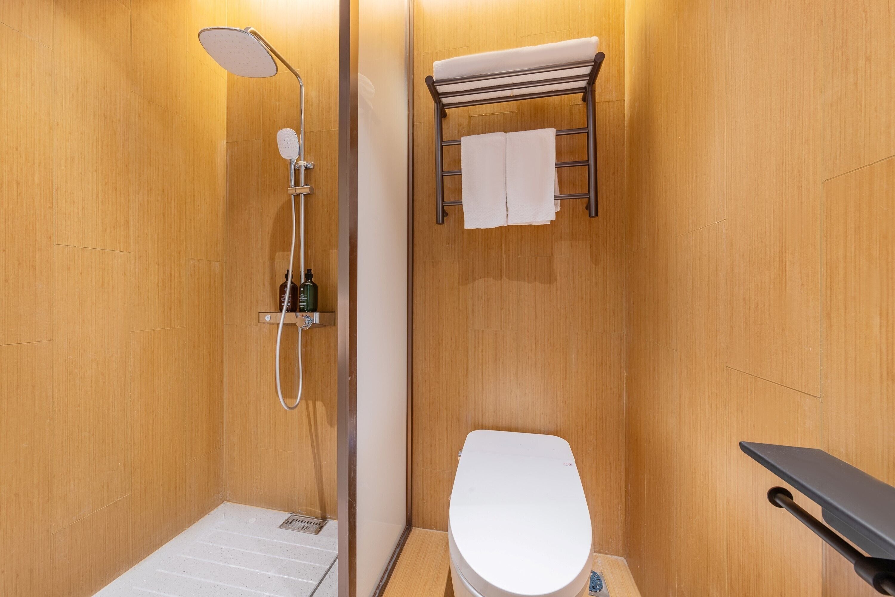 Une petite salle de bain compacte, équipée d’une douche, de toilettes et d’un porte-serviettes.