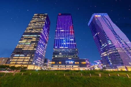 Three high-rise buildings with illuminated facades, one prominently displaying 'YI BO HOTEL'.