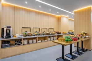 A buffet setup with multiple food stations, a coffee machine, and a variety of beverages.