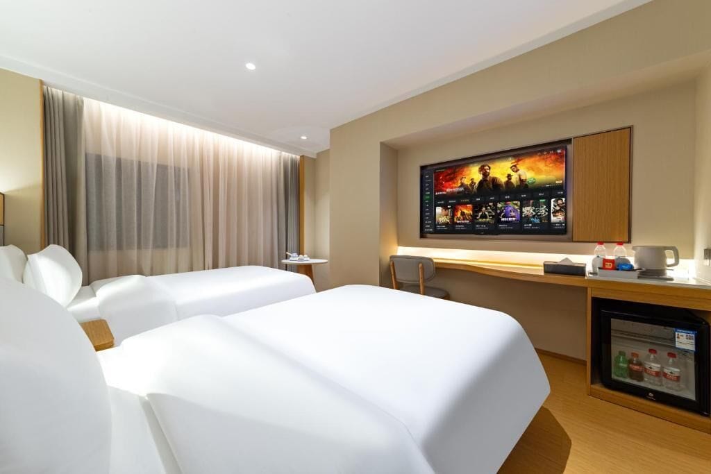 Habitación de hotel con dos camas, un escritorio, televisor y minibar.
