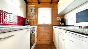 Eine Küche mit Holzwänden, einem Fenster, einer Kaffeemaschine und einem Fernseher.