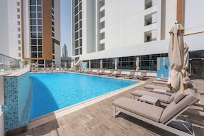 A rooftop swimming pool with lounge chairs and umbrellas, surrounded by modern buildings. - Free housekeeping visits during your stay - StayShort - Chic Modern Studio That Sleeps 3 at Riviera Beachfront (Meydan)
