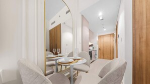 Una zona de menjador moderna amb una taula rodona, cadires i una cuina al fons.