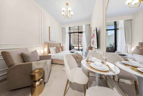 A modern hotel room with a sofa, dining table, and a view of the cityscape. - Free housekeeping visits during your stay - StayShort - Chic Modern Studio That Sleeps 3 at Riviera Beachfront (Meydan)