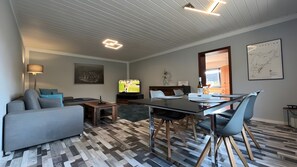 Ein modernes Wohnzimmer mit Sofa, Fernseher, Esstisch und Stühlen.