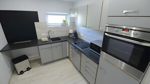 Eine moderne Küche mit Einbauofen, Kaffeemaschine und Fenster.
