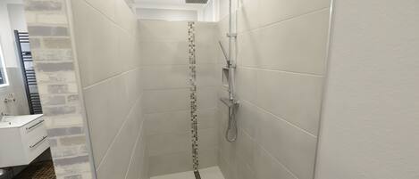 Une salle de bain moderne avec une douche, des murs carrelés et un espace lavabo bien visible.