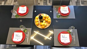 Ein Tisch mit roten Tellern, klaren Gläsern und einer Weinflasche, dekoriert mit einem Obstschalen-Zentrum.