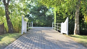 Un chemin pavé mène à une entrée fermée par un portail, qui est elle-même entourée d’arbres.