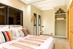 Un dormitorio con cama, almohadas, una mesita de noche, un espejo y un armario.