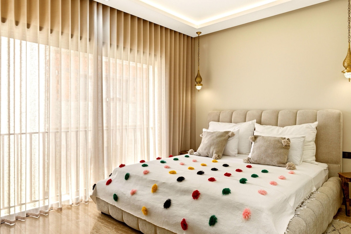 A bedroom with a bed, curtains, and a hanging light fixture.