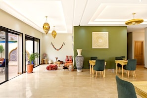 A spacious living area with a dining set, decorative vases, and a large wall art piece.