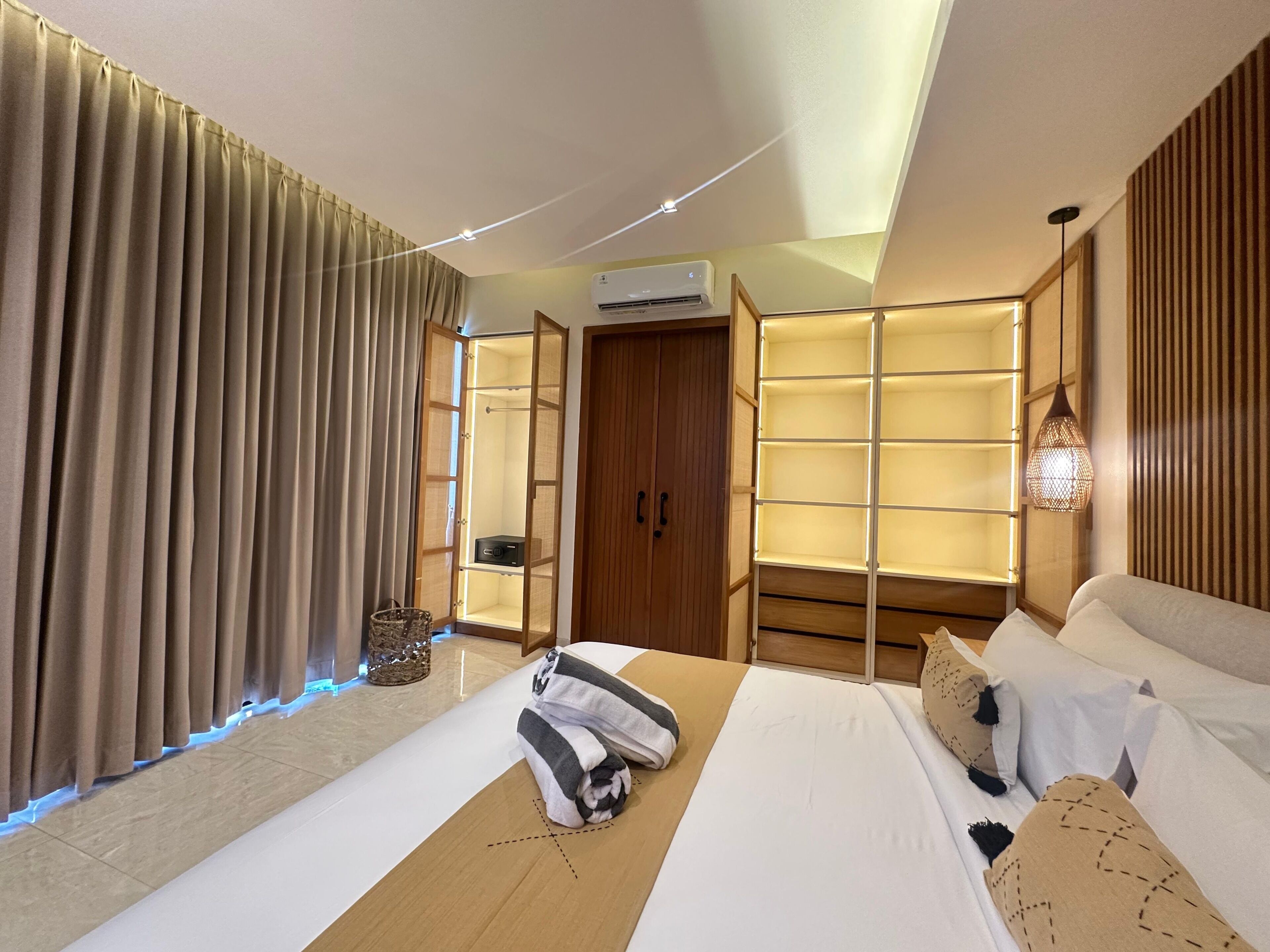 Une chambre d’hôtel avec un lit, une armoire, une coiffeuse et un luminaire au plafond.