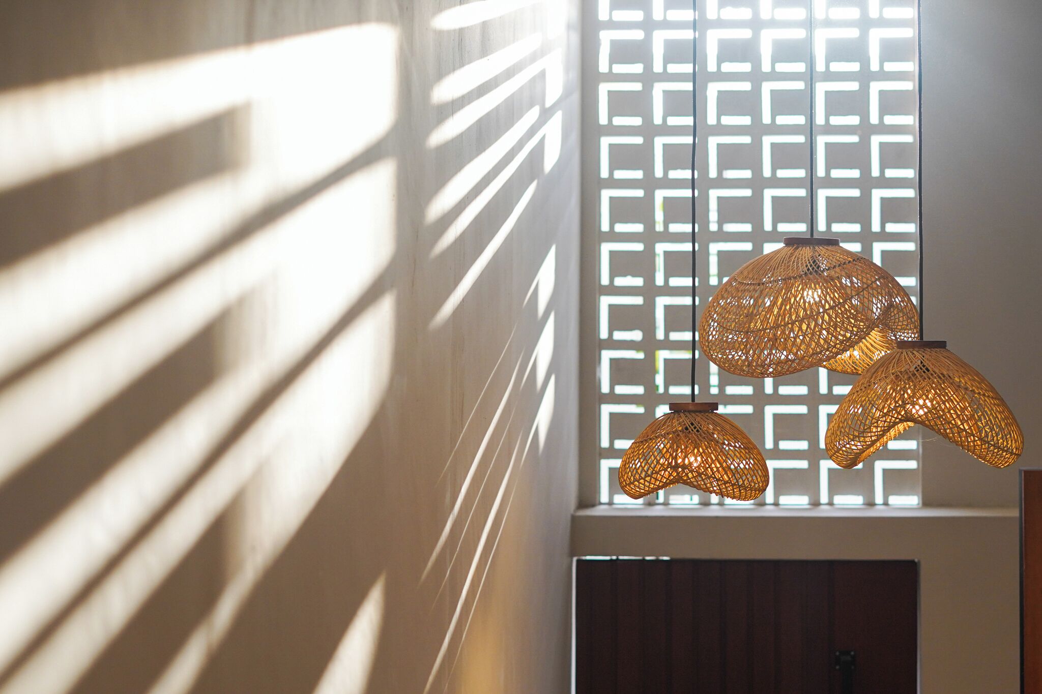 A room with a geometric patterned wall, a door, and a hanging woven light fixture.