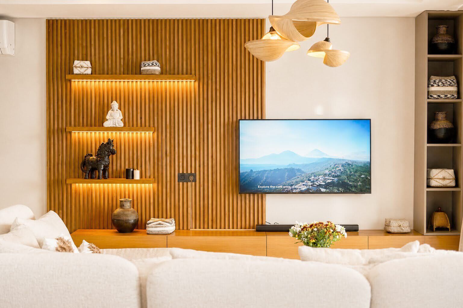 Una sala de estar moderna con una pared de acento de madera, un televisor montado y un sofá.