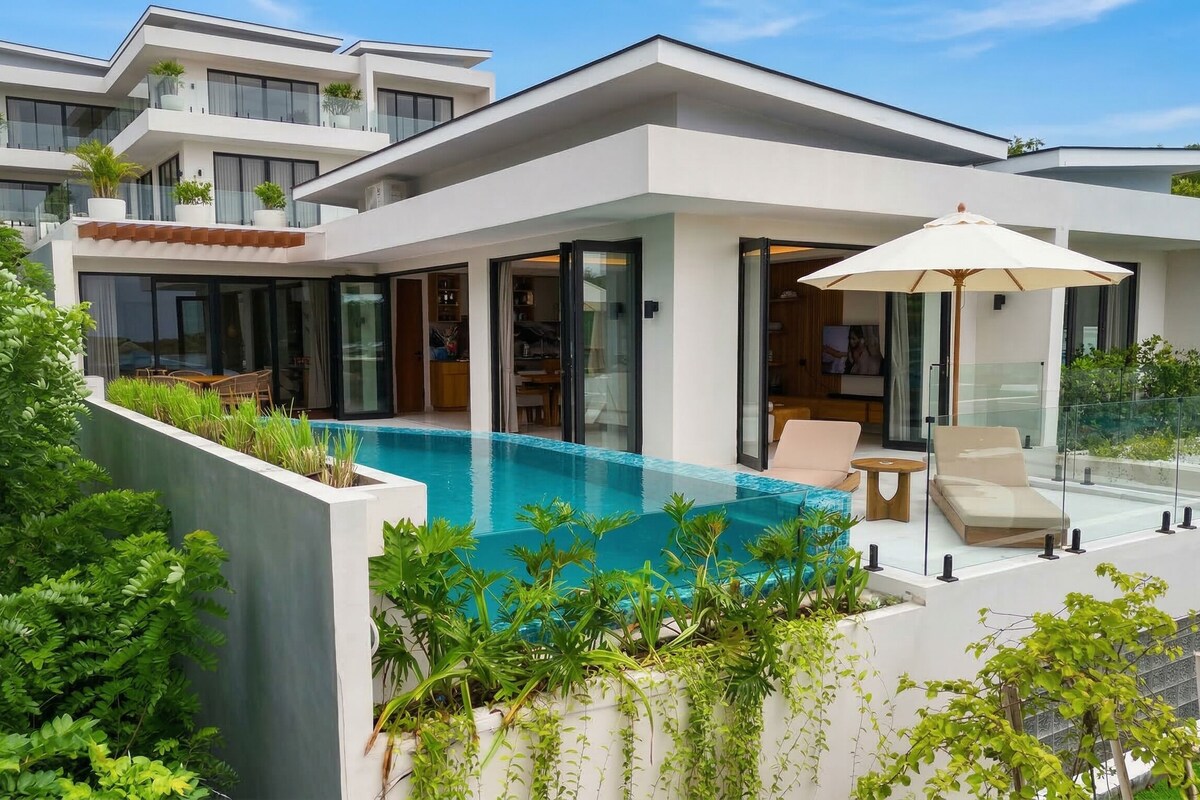 Ein modernes, zweistöckiges Haus mit Swimmingpool, Glasgeländern und Gartenmöbeln.