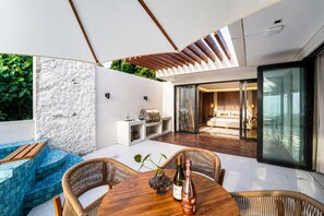A modern outdoor living area with a dining table, chairs, and a grill. - Zen Hillside Oceanview Bali (Badung)