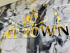 A marble wall with 'LEE TOWN' and 'MH GROUP' logos. - Hotel Lee Town (Ahmedabad)