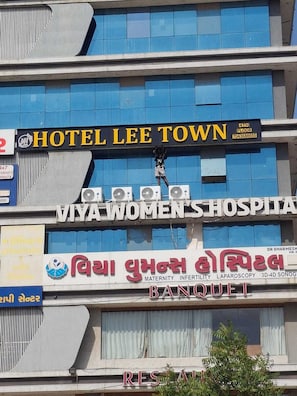 A building with multiple signs, including 'Hotel Lee Town,' 'Viya Women's Hospital,' and 'Banqueet.' - Hotel Lee Town (Ahmedabad)