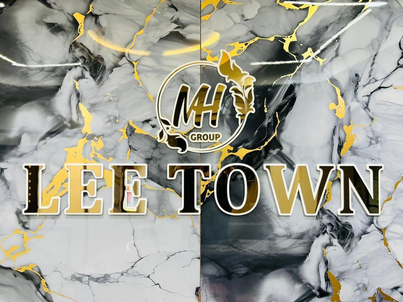 Logo con il testo 'MH GROUP' e 'LEE TOWN' su sfondo marmorizzato.
