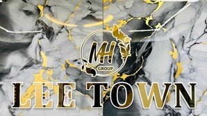 Een logo met 'MH GROUP' en de tekst 'LEE TOWN' op een marmeren achtergrond.