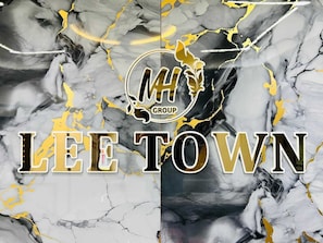 A logo with 'MH GROUP' and the text 'LEE TOWN' on a marble background. - Hotel Lee Town (Ahmedabad)