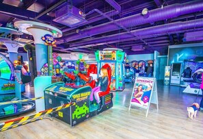 Eine Indoor-Spielhalle mit verschiedenen Spielautomaten, darunter ein Space Invaders-Spiel.
