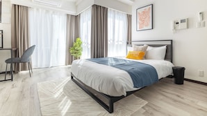 A modern hotel room with a large bed, a desk, and a chair. - Dash Living Ryogoku (Sumida City)