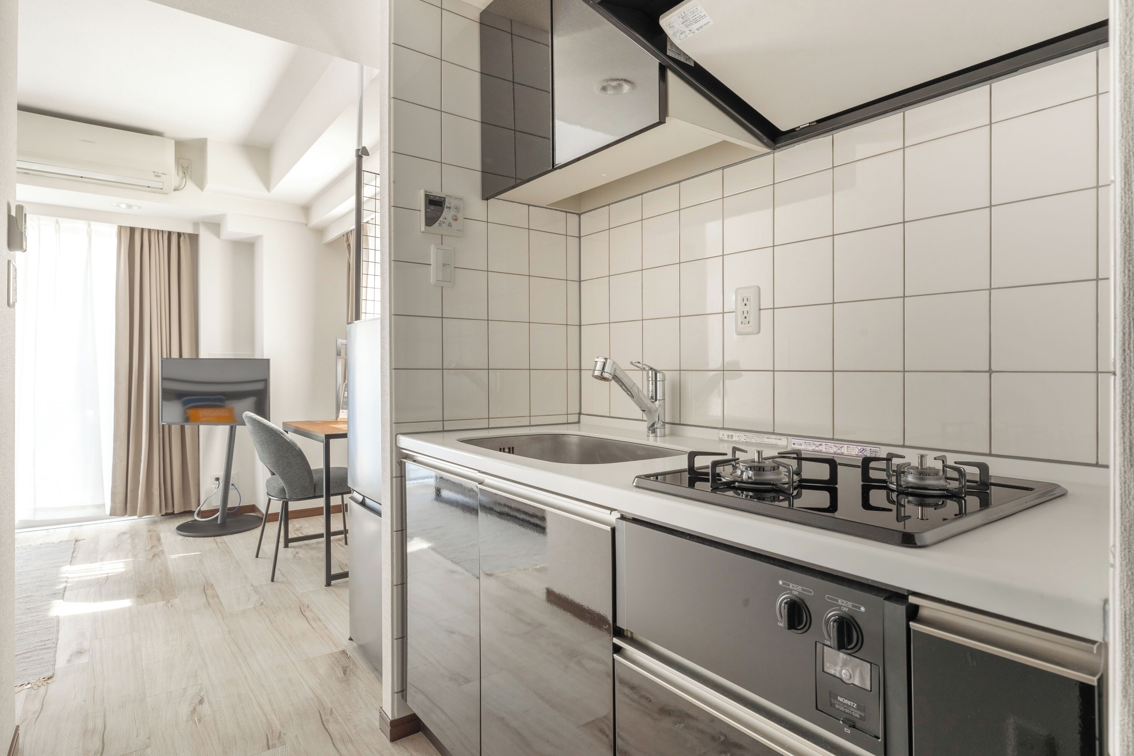 A modern kitchen with a gas stove, stainless steel appliances, and a large window.